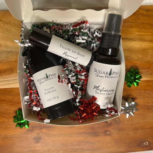 Set of skincare products including lip balm and shave oil in a decorative box on a wooden surface.