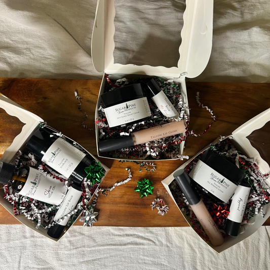 Three gift boxes with skincare products on a wooden surface.