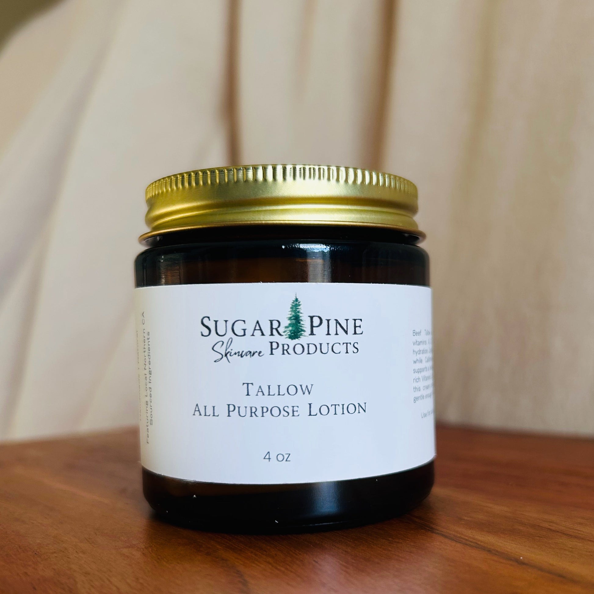 Small jar of all-purpose lotion with a gold lid on a wooden surface. sugar pine products all purpose tallow lotion